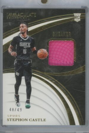A collectible basketball card featuring Stephon Castle in a black uniform, dribbling a ball. The card includes a small patch of pink sneaker material and is marked 48/49 with gold and white accents.