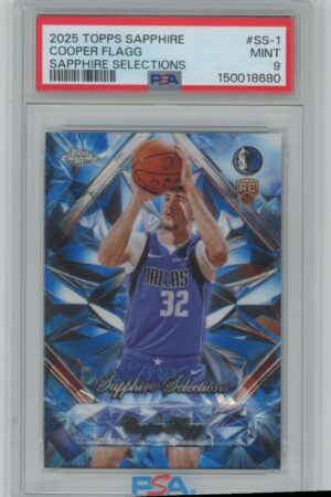 A 2025 Topps Sapphire Selections basketball card of Cooper Flagg in a PSA case, graded Mint 9. The card shows Flagg in a blue Dallas Mavericks uniform, preparing to shoot a basketball.