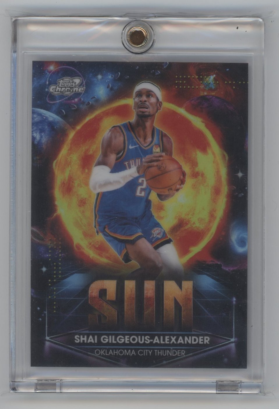 Basketball player in Thunder jersey dribbles in front of a large sun graphic. The card reads SUN and SHAI GILGEOUS-ALEXANDER OKLAHOMA CITY THUNDER. Card is encased in a protective plastic sleeve.